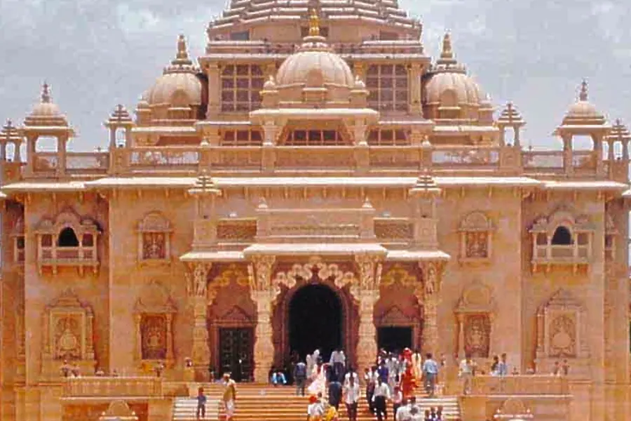A carved sandstone temple with visitors gathered on the steps in front
