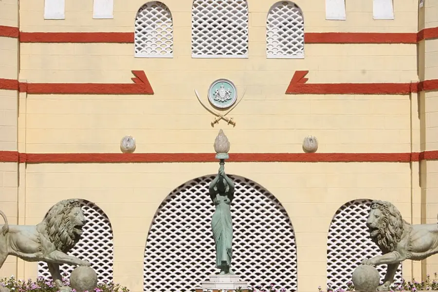 A pale ornate facade with stone lions flanking an arched entrance