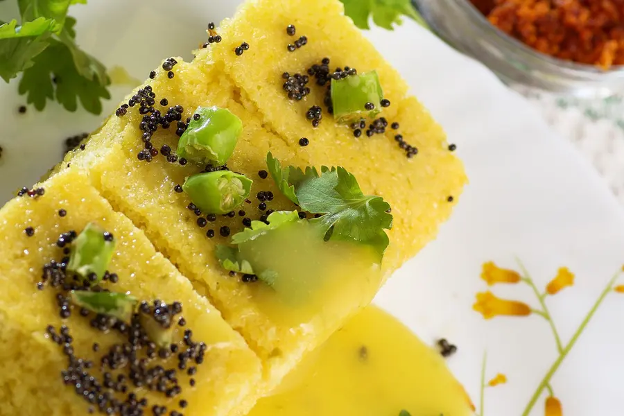 Squares of soft yellow khaman topped with mustard seeds and coriander