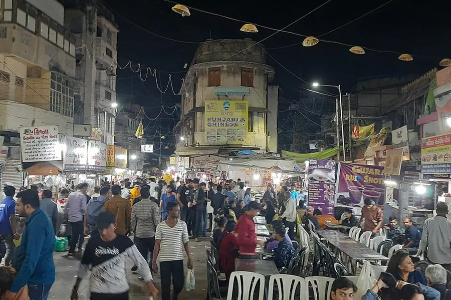 A square packed with people and lit food stalls at night
