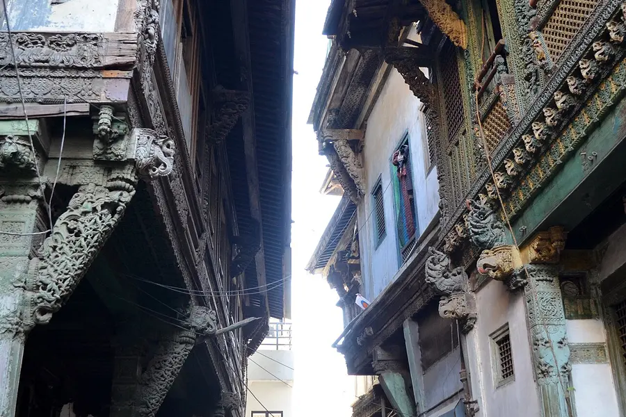 A narrow lane between old houses with carved wooden brackets and balconies overhead