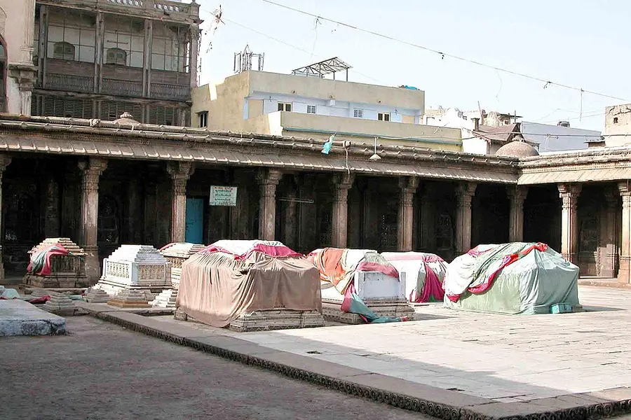 Cloth-covered tombs in an open colonnaded courtyard ringed by buildings