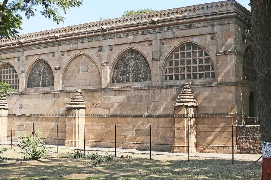 The long arcaded stone wall of a mosque with a row of arched windows