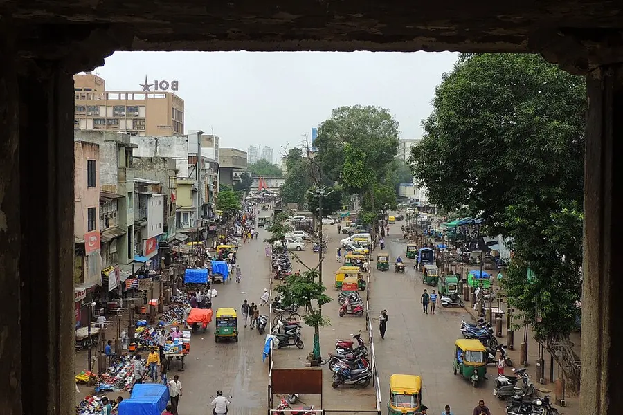 A busy street seen through the arch of an old stone gateway